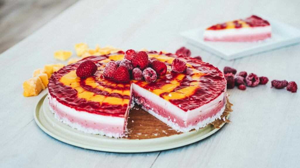 No-bake AIP triple-layer coconut “cheesecake” presented on a plate. One piece is missing; it is on its own plate in the background.